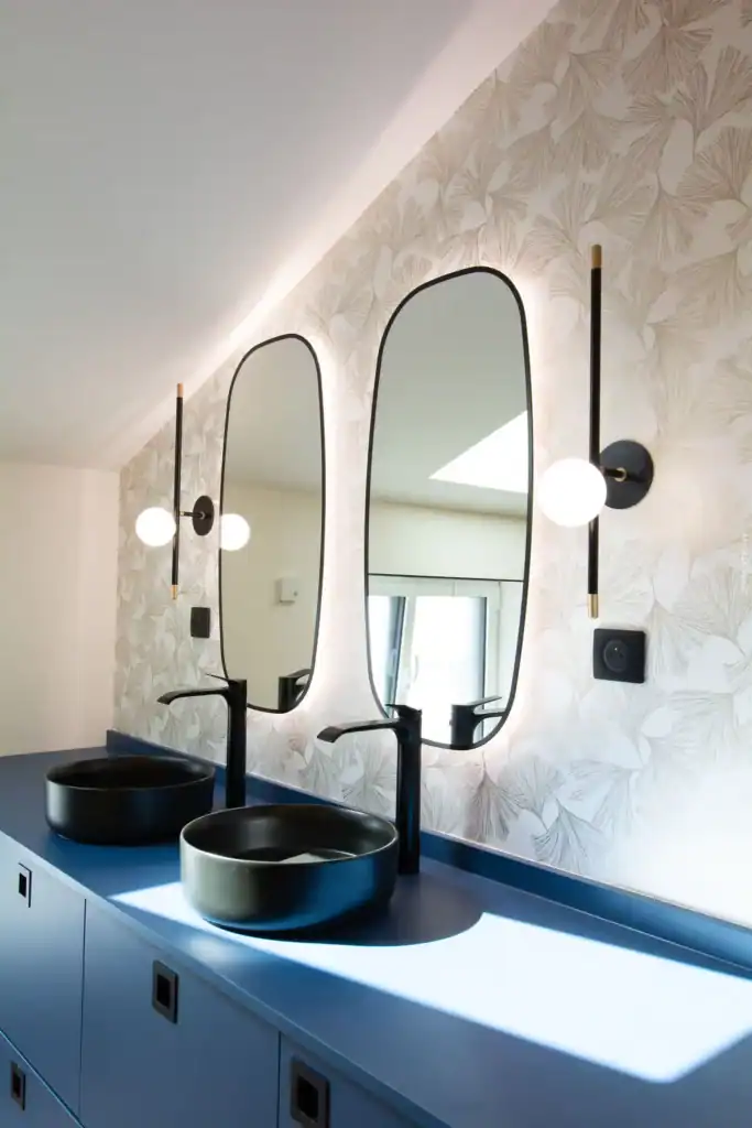Lavabo design avec miroir ovale et appliques modernes dans salle de bain élégante.