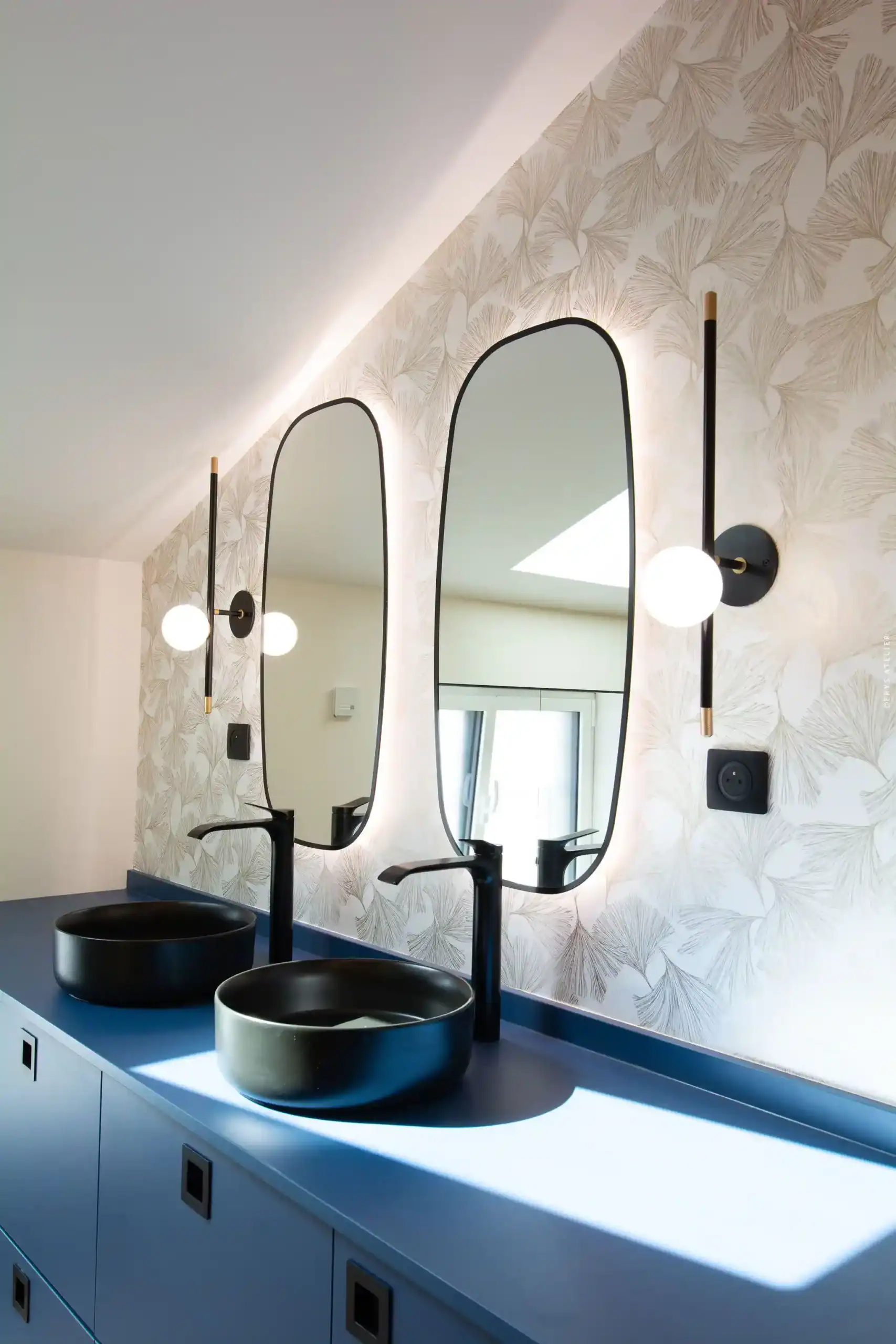 Lavabo design avec miroir ovale et appliques modernes dans salle de bain élégante.