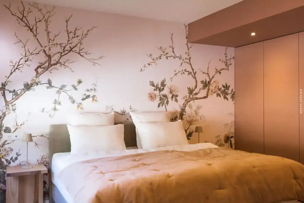 Chambre avec mur en papier peint floral, lit double et lampes de chevet modernes.