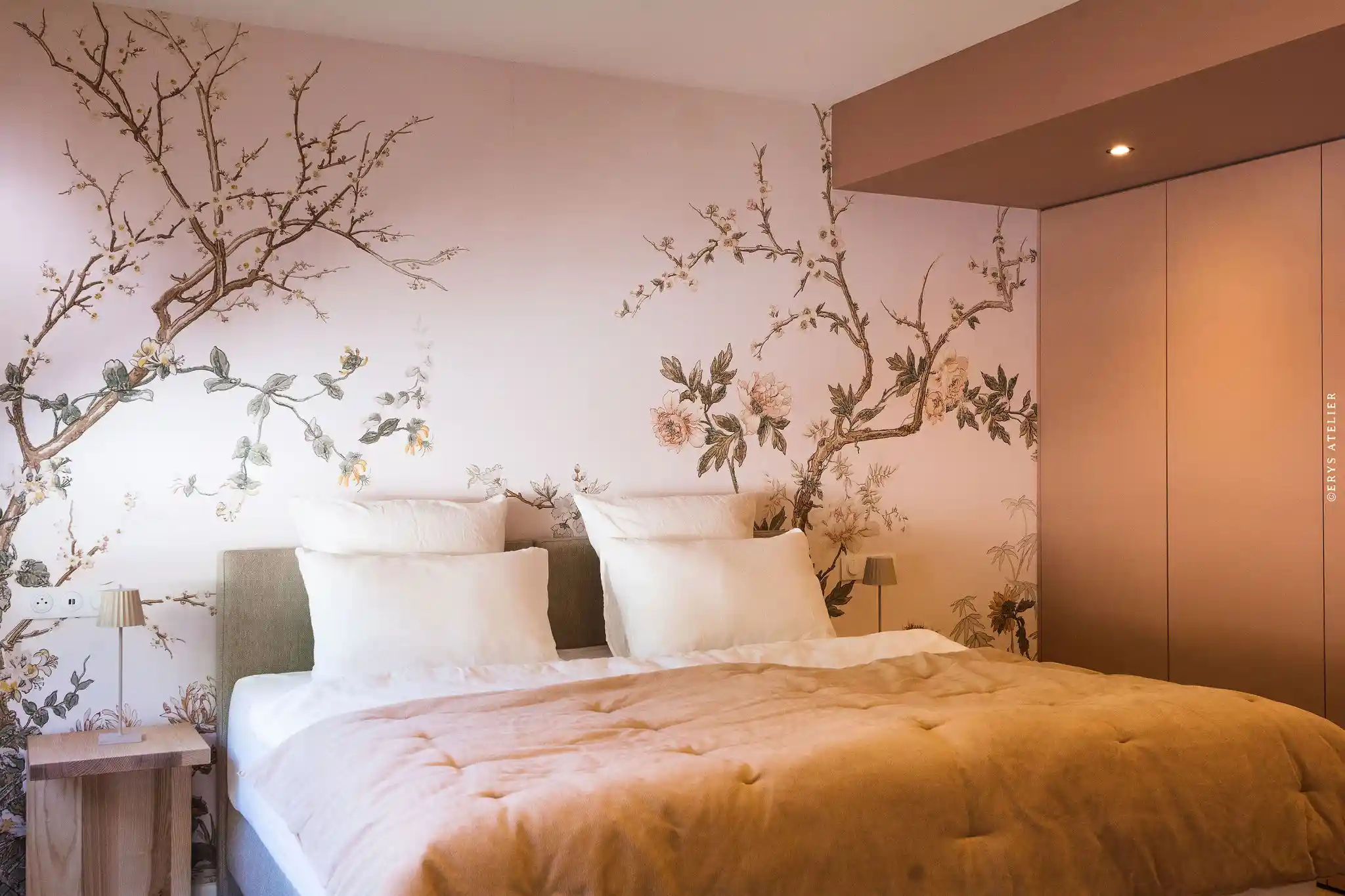 Chambre avec mur en papier peint floral, lit double et lampes de chevet modernes.