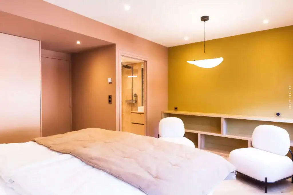 Lit dans une chambre contemporaine avec mur vert pastel et mobilier moderne.