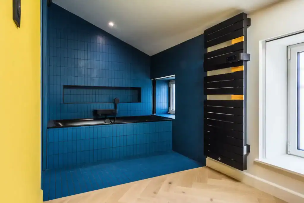 Salle de bain moderne avec baignoire, carrelage bleu et radiateur mural