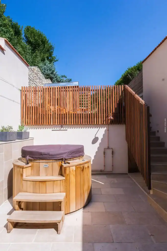 Bain à remous en bois dans un espace extérieur privatif avec clair-vallon et vue sur le ciel bleu.
