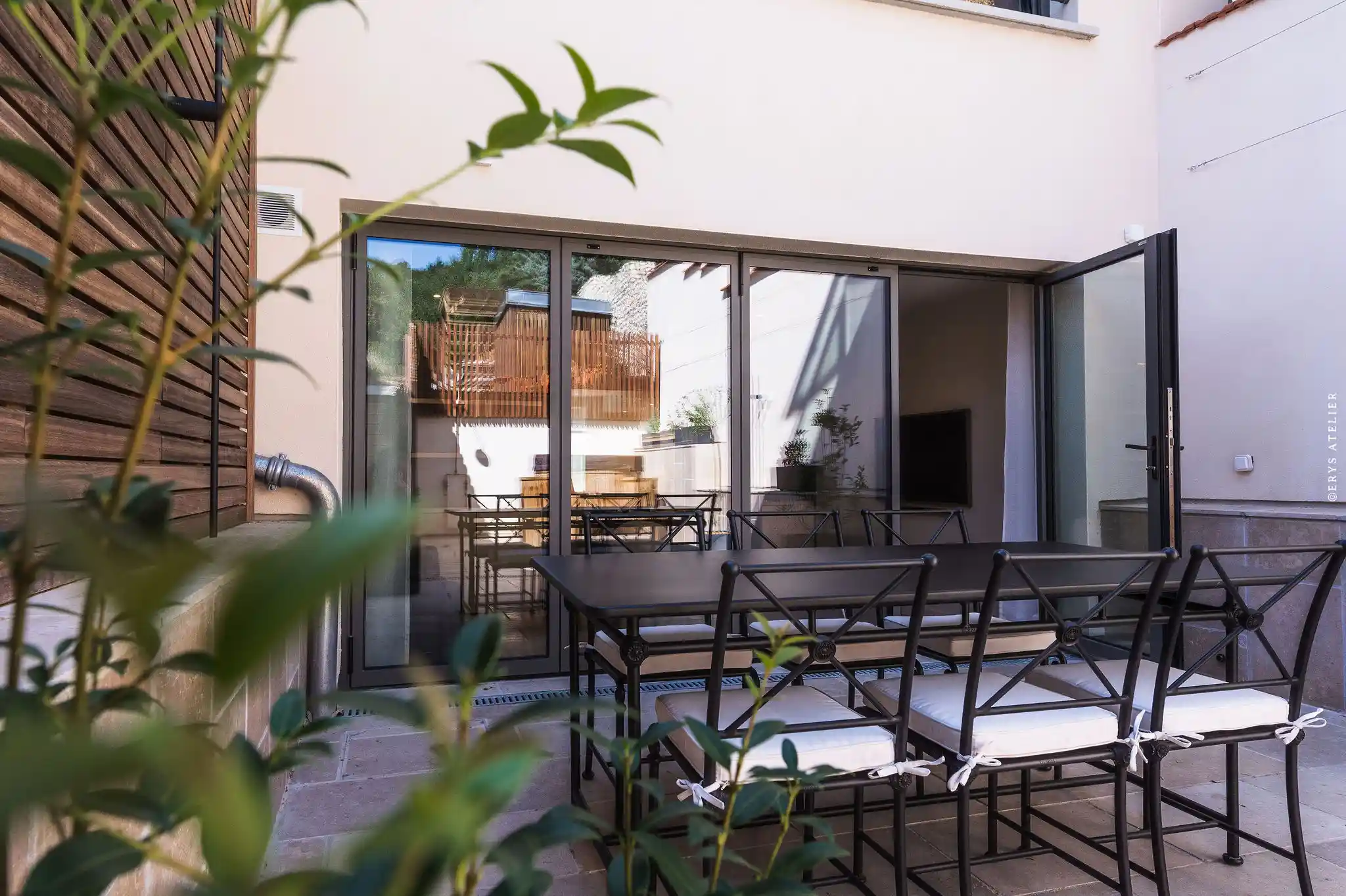 Façade d'une chambre avec terrasse extérieure et mobilier design, vue sur le jardin clos et paysager.