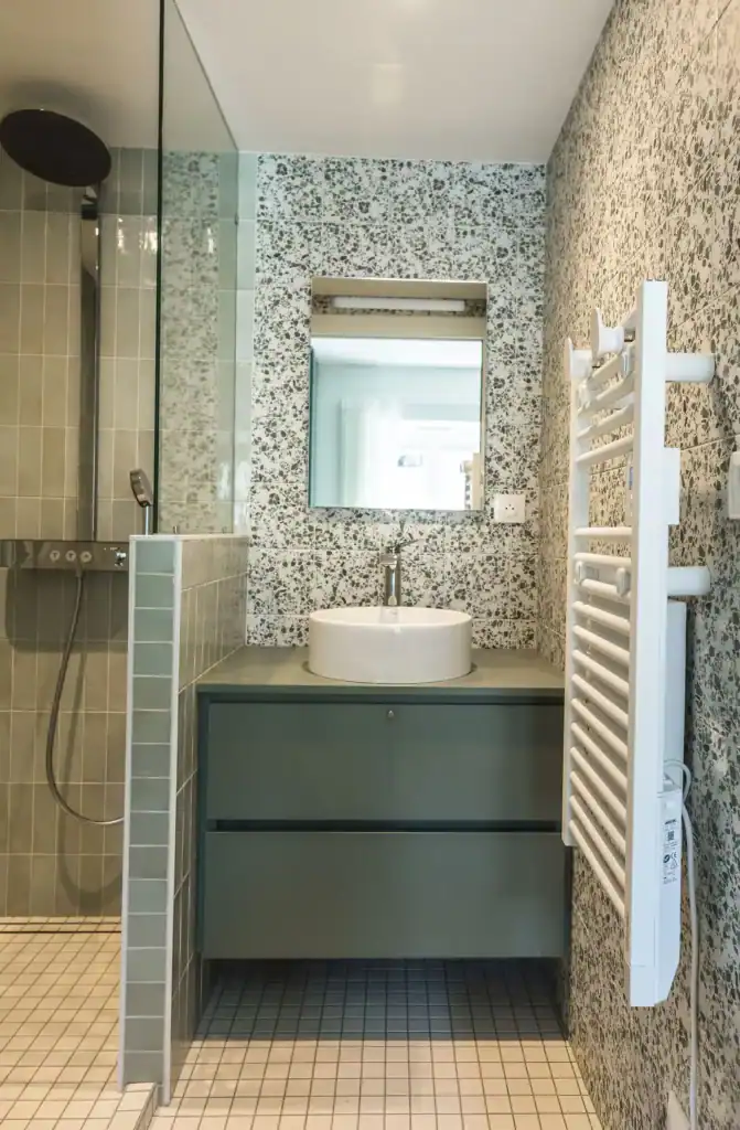 Lavabo rond moderne dans salle de bains avec miroir et radiateur électrique blanc.