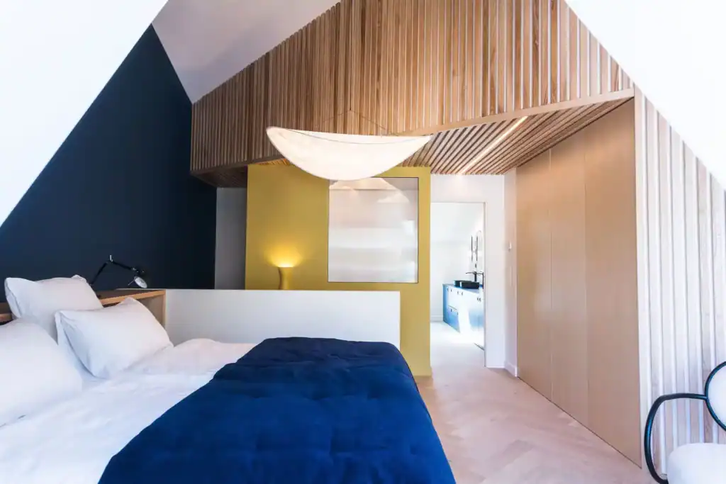 Lit moderne avec décoration épurée, mur bleu foncé et lampe suspendue en tissu blanc.