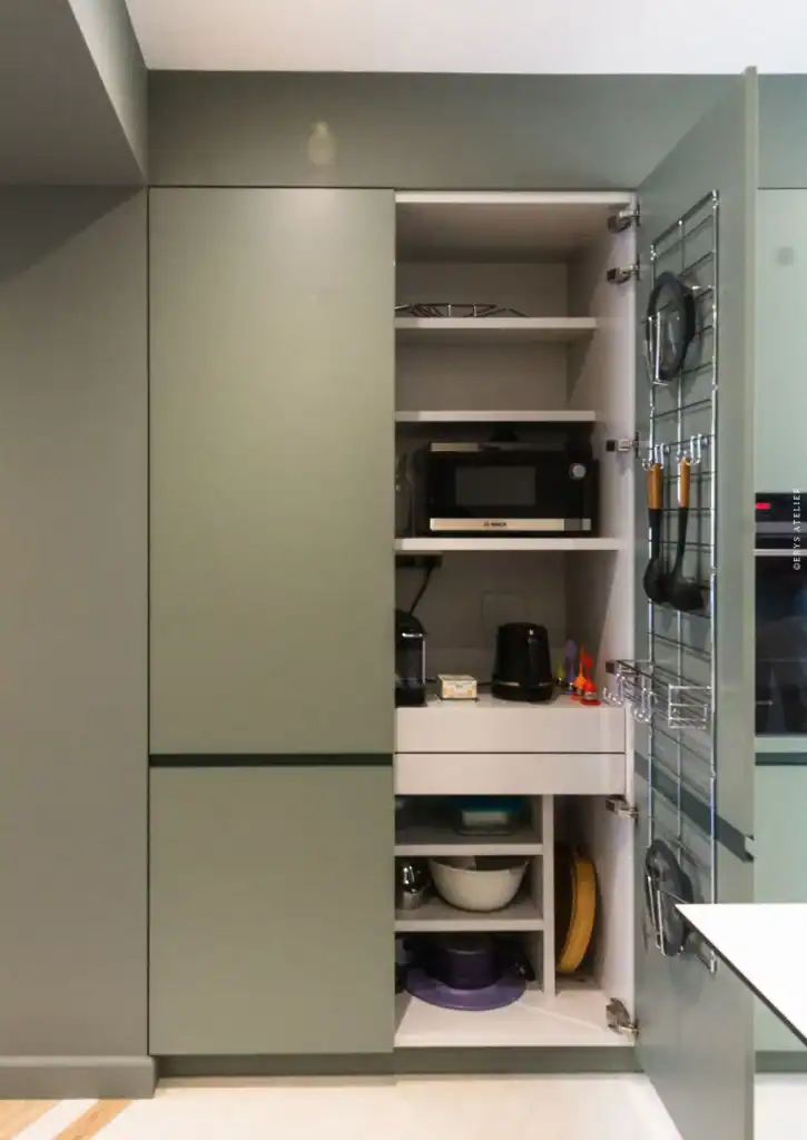 Micro-ondes encastré dans un meuble de cuisine moderne vert gris.