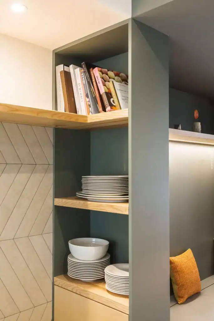 Plats de cuisine en porcelaine blanche empilés sur des étagères en bois dans une cuisine moderne.