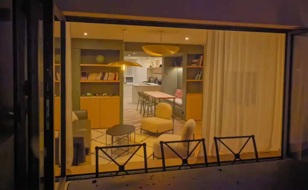 Moderne intérieur d'une maison avec salon, cuisine et espace repas, vue depuis une baie vitrée.